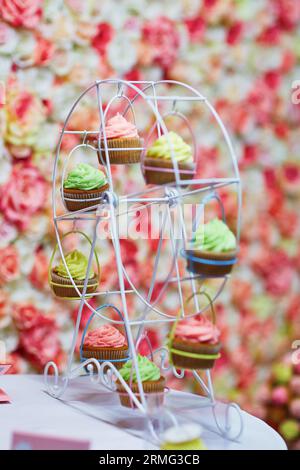 Bunte Cupcakes auf einem kleinen Riesenrad, wunderschöne Tischdekoration für Party oder Hochzeitsempfang Stockfoto