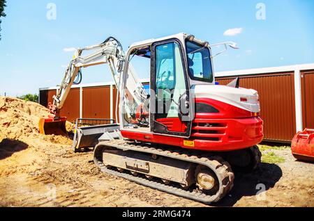 Bagger arbeitet im Hochland. Stellt einen Graben für die Kommunikation dar. Wasser und Strom. Stockfoto