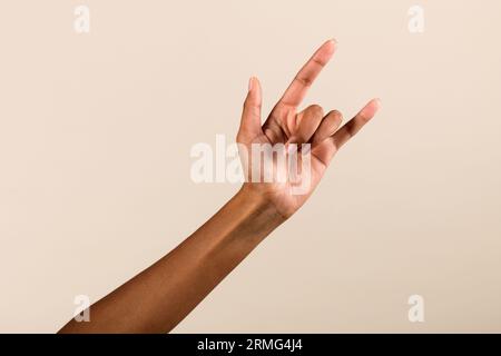 Hand von Afroamerikanerin mit Hornzeichen vor grauem Hintergrund im Studio Stockfoto