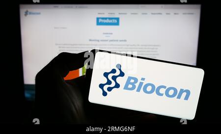 Person, die ein Mobiltelefon mit dem Logo des indischen biopharmazeutischen Unternehmens Biocon Limited auf dem Bildschirm vor der Webseite hält. Konzentrieren Sie sich auf das Display des Telefons. Stockfoto