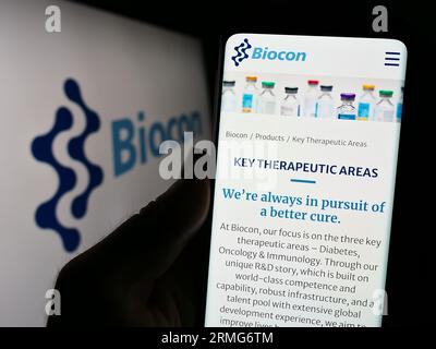 Person, die ein Smartphone mit Webseite des indischen biopharmazeutischen Unternehmens Biocon Limited auf dem Bildschirm mit Logo hält. Konzentrieren Sie sich auf die Mitte der Telefonanzeige. Stockfoto