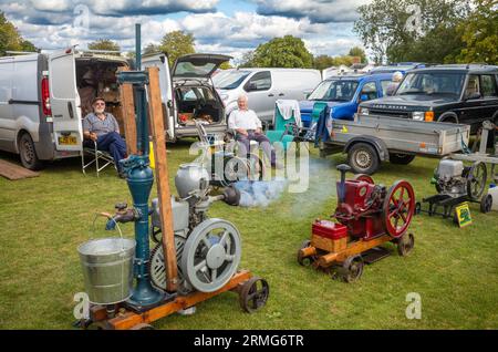 Zwei ältere männliche Liebhaber von stationären Oldtimer-Motoren sitzen und zeigen ihre Maschinen auf einem Dorffest in Wisborough Green, West Sussex, Großbritannien. Stockfoto