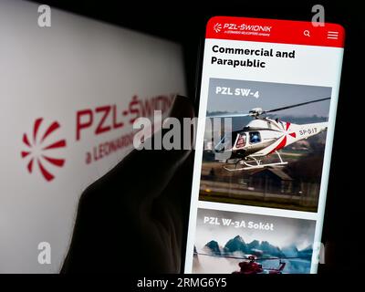 Person, die ein Mobiltelefon mit der Website des polnischen Verteidigungsunternehmens PZL-Swidnik S.A. vor dem Logo auf dem Bildschirm hält. Konzentrieren Sie sich auf die Mitte der Telefonanzeige. Stockfoto
