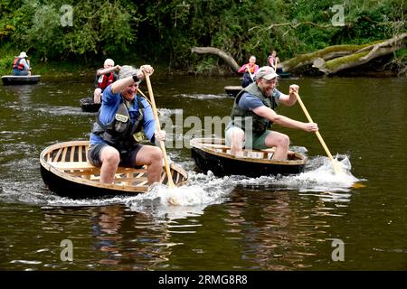 Ironbridge, Shropshire, Großbritannien. Coracle Regatta. August 28 2023. Die Ironbridge Bank Holiday Coracle Regatta Alison Milburn (links) manövriert ihren männlichen Konkurrenten, um den Sieg auf dem Fluss Severn zu erringen. Quelle: DAVE BAGNALL / Alamy Live News Stockfoto