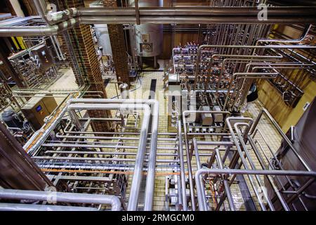 Moderne Brauerei-Produktionslinie. Industriefässer aus Stahl, die durch Rohrleitungen miteinander verbunden sind. Stockfoto