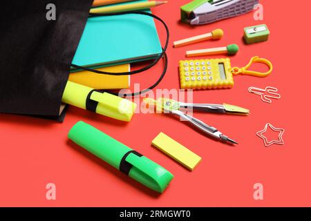 Papiertasche mit buntem Schreibpapier auf rotem Hintergrund, Nahaufnahme Stockfoto