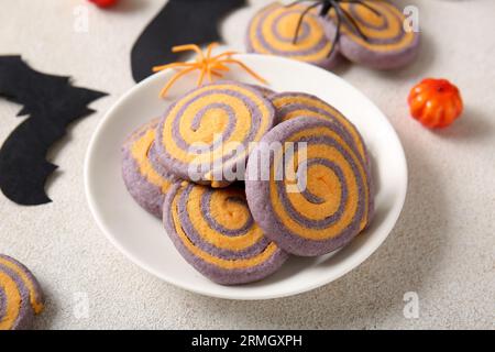 Teller mit leckeren Keksen und Halloween-Deko auf weißem Hintergrund Stockfoto