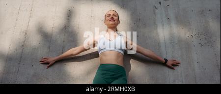 Porträt einer jungen Sportlerin, die vor einer Betonwand in der Stadt steht. Stockfoto