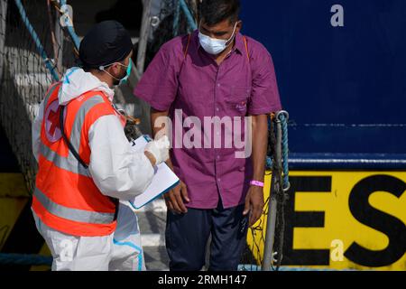 Livorno, Italien. 27. August 2023. Der an der Küste Libyens geborene Migrant 50 verlässt das Schiff Humanity 1, während ein Rote-Kreuz-Operator seine Ankunft im Hafen von Livorno registriert.das Schiff Humanity 1 der deutschen NRO United 4 Rescue und SOS Humanity, er musste mehr als 1.000 Kilometer zurücklegen, um den vom italienischen Innenministerium zugewiesenen sicheren Hafen zu erreichen. Seit dem Inkrafttreten des "NRO-Dekrets" sind die Ausschiffungshäfen von NRO-Schiffen zunehmend von den Rettungszonen entfernt. (Bild: © Marcello Valeri/ZUMA Press Wire) EDITORIAL Stockfoto