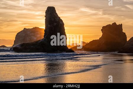 Goldenes Licht umgibt die Stacks des Meeres und spiegelt sich im Pazifischen Ozean am Bandon Beach in Bandon, Oregon Stockfoto