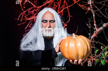 Halloween-Horror. Männlicher Dämon mit Jack-o-Laterne. Teufelsvampirmann mit Halloween-Kürbis. Zauberer hexer alter Mann mit Kürbis an Halloween Nacht Stockfoto