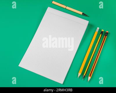 Bürodesign. Öffnen Sie Notizbuch, Stifte und Stift auf grünem Hintergrund. Stockfoto