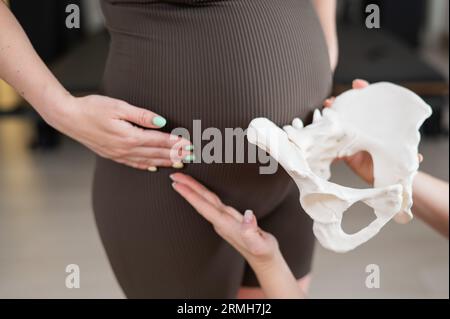 Doula erklärt den Geburtsvorgang an einer Probe des Beckens einer schwangeren Frau. Stockfoto