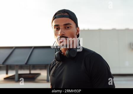 Nahaufnahme eines jungen männlichen Athleten, der eine Kappe und kabellose Kopfhörer trägt Stockfoto