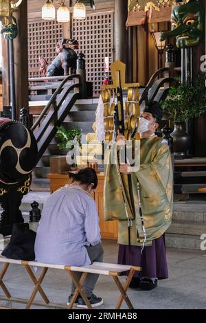 Japan, Fukuoka, Hakata. Shinto-Priester, der eine Zeremonie für einen Anbeter im Kushida-Shinto-Schrein durchführt. Stockfoto