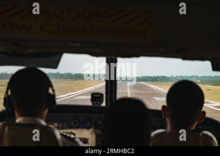 Silhouetten von Passagieren gegen die Start- und Landebahn, die in einem kleinen Flugzeug am Philip S.W. Goldson International Airport in Belize City landen Stockfoto