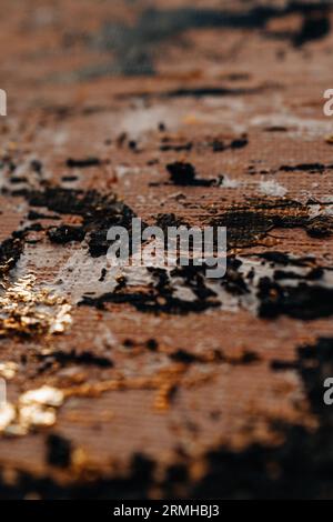 Abstrakte, moderne schwarze Ölstriche und glänzende, goldglänzende Bronzetextur. Künstlerischer Hintergrund. Pinselstrich abschmieren Stockfoto