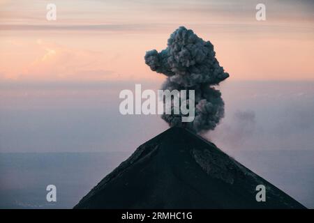 Eine Rauch- und Aschewolke bricht beim Sonnenaufgang aus dem Fuego Vulkankrater aus, wie vom benachbarten Vulkan Acatenango in Guatemala aus gesehen Stockfoto