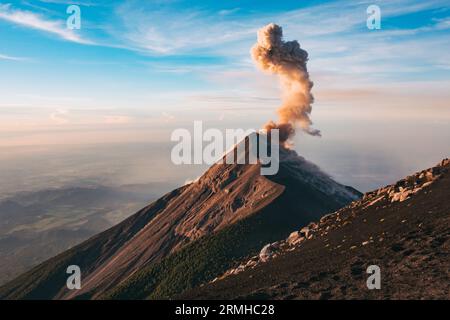 Eine Rauch- und Aschewolke bricht beim Sonnenaufgang aus dem Fuego Vulkankrater aus, wie vom benachbarten Vulkan Acatenango in Guatemala aus gesehen Stockfoto