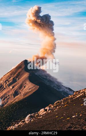 Eine Rauch- und Aschewolke bricht beim Sonnenaufgang aus dem Fuego Vulkankrater aus, wie vom benachbarten Vulkan Acatenango in Guatemala aus gesehen Stockfoto