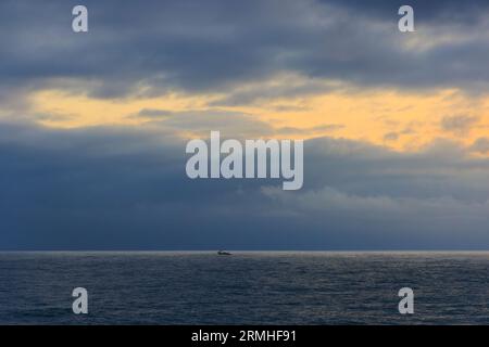 Kleines Fischereifahrzeug im riesigen blauen Meer bei Sonnenaufgang. Hochwertige Fotos Stockfoto