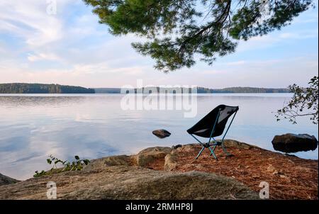 Ein leichter Campingstuhl sitzt auf einer Insel mit Blick auf einen See im Algonquin Park. Stockfoto