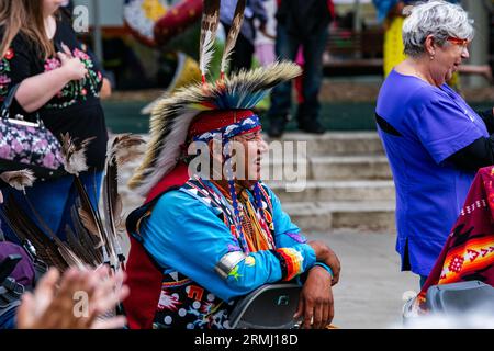 Ein älterer, der ein Kleid trägt, beobachtet, wie die Teilnehmer am runden Tanz teilnehmen. Als das Pride Weekend in Edmonton beginnt, erkennt die indigene Gemeinschaft das Ereignis mit dem 2 Spirit Powwow an. Der Begriff Two-Spirit ist eine direkte Übersetzung des Ojibwe-Begriffs Niizh manidoowag. „Zweigeist“ oder „Zweigeist“ wird üblicherweise verwendet, um eine Person zu bezeichnen, deren Körper gleichzeitig einen männlichen und einen weiblichen Geist beherbergt. Ein Teil der Feier ist die Inklusivität aller und die Begrüßung aller zum Feiern, indem sie in einem Jig-Tanz konkurrieren. Alle Teilnehmer sind zur Teilnahme an Preisgeldern eingeladen. Das ist t Stockfoto