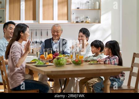 Mehrere Generationen asiatischer Familien unterhalten sich, während sie zu Hause zusammen essen Stockfoto