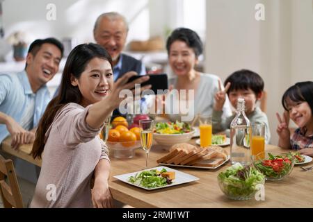 Drei Generationen asiatischer Familie nehmen ein Selfie, während sie zusammen essen Stockfoto