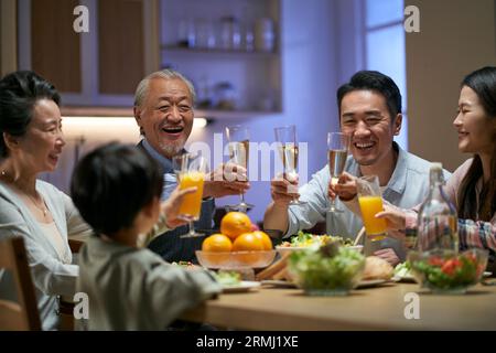 Eine asiatische Familie aus drei Generationen zu Hause, die den Urlaub mit einem Toast feiert Stockfoto