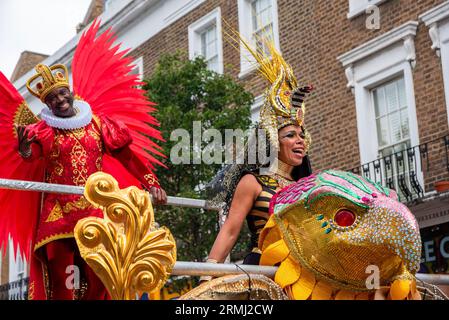 Eine weibliche und eine männliche Samba-Tänzerin stehen auf einem Anhänger. Die Frau ist als Kleopatra, die Königin von Ägypten, und der Mann ist als König des Vereinigten Königreichs gekleidet. Der Notting Hill Carnival ist eines der größten Straßenfeste der Welt. Es begann 1966, entstand aber aus dem Karibischen Karneval, der 1959 mit der Immigrantengemeinschaft aus Trinidad und Tobago organisiert wurde. In diesem Jahr feiert der Notting Hill Carnival den 50. Jahrestag der Einführung der Soundsysteme und Mas-Bands. Es ist auch der 75. Jahrestag der Ankunft der Passagiere der Empire Windrush Stockfoto