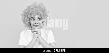 Verträumte freaky Frau in lockigen Clown Perücke für Party, träumen. Frau isoliert Gesicht Porträt, Banner mit Kopieplatz. Stockfoto