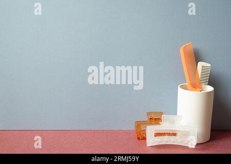 Friseur-Werkzeug. Haarbürste und Haarnadel auf rotem Tisch. Grauer Hintergrund Stockfoto