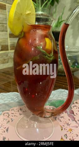 Ein Glaskrug gefüllt mit einem zitrusartigen Getränk, garniert mit einem einzelnen Zitronenkeil Stockfoto
