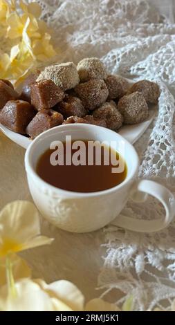 Ein kleiner Teller mit einer Auswahl frisch gebackener Zuckerkekse und einer Tasse Tee Stockfoto