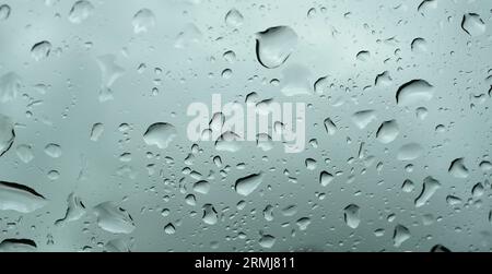 Viele Regentropfen auf durchsichtigem Glas, Wassertropfen draußen in der Regenzeit Stockfoto