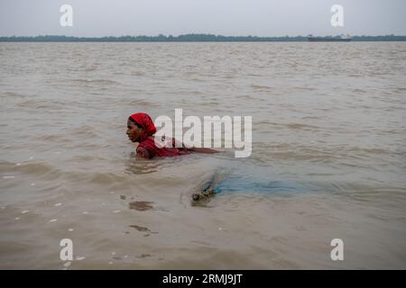 Khulna, Bangladesch. 26. August 2023. Eine Frau sah Angeln auf dem Fluss Shibsha. Fischerei und Krabbenfang sind die Haupteinnahmequellen in Kalabogi in Khulna, Bangladesch. Vor nicht allzu langer Zeit war Kalabogi, ein Küstendorf in Bangladesch, voll von kultivierbarem Land, bis der Anstieg des Meeresspiegels begann, das Gebiet bis zur Bucht von Bengalen zu verschlingen. Häufige Zyklone und Überschwemmungen haben das Dorf seit den späten 1990er Jahren getroffen 2009 zerstörte ein großer Zyklon namens Aila die 1.400 Kilometer Dämme, 8.800 Kilometer Straßen und etwa 50.000 Hektar Ackerland. Mehrere Hundert p Stockfoto