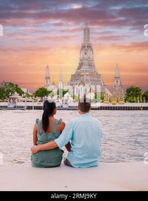 Wat Arun Tempel Bangkok während des Sonnenuntergangs in Thailand. Chao Praya bei Sonnenuntergang. Ein paar Männer und eine Frau sind auf einer Städtereise nach Bangkok Thailand und beobachten den Sonnenuntergang am Fluss Stockfoto