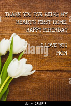 Komposit aus weißen Blumen und Happy Birthday, i Love You Mom Text auf Holztisch Stockfoto