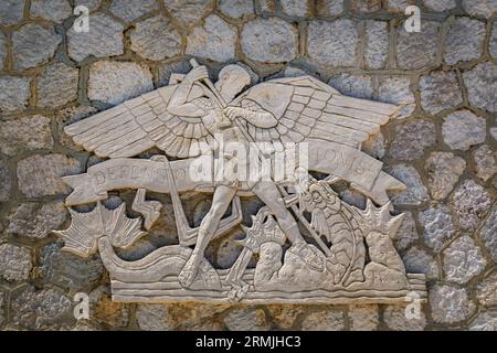 Menton, Frankreich - 26. Mai 2023: Skulptur des Hautarreliefs, in der der Heilige Georg den Drachen an einer Steinmauer tötete. In der Inschrift steht der Verteidiger von Menton Stockfoto
