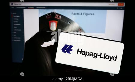 Person mit Smartphone mit Logo der deutschen Reederei Hapag-Lloyd AG auf dem Bildschirm vor der Website. Konzentrieren Sie sich auf das Display des Telefons. Stockfoto