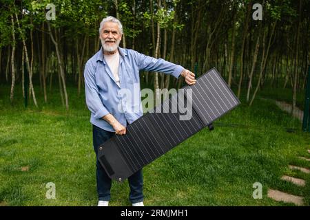 Reifer Mann, der Solarzellen im Garten hält. Stockfoto