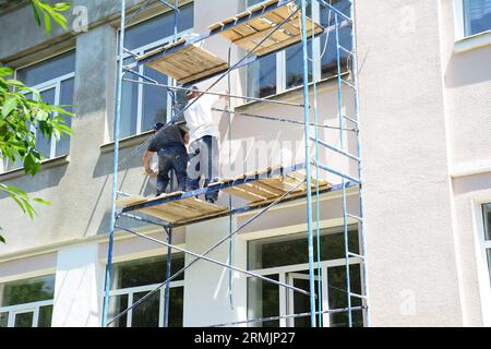 Malen von Hauswänden. Bauunternehmer reparieren und lackieren Außenwände. Hausrenovierung mit Putz- und Malwänden. Stockfoto