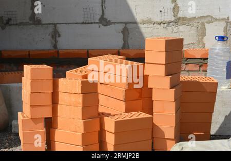 Haufen Tonziegel und Flasche mit Weichmachern für Beton. Weichmacher sind die Zusätze, die verwendet werden, um Zement zu mischen, um ihre Qualität und mA zu verbessern Stockfoto