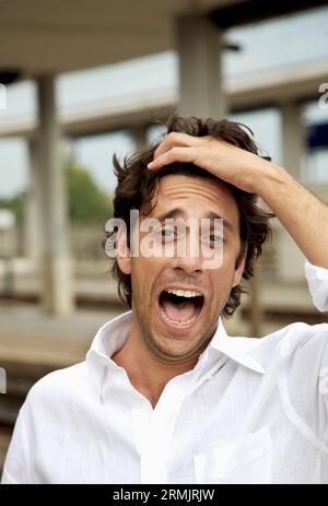 Lachender junger Mann auf der Station, der Haare zurückzieht Stockfoto