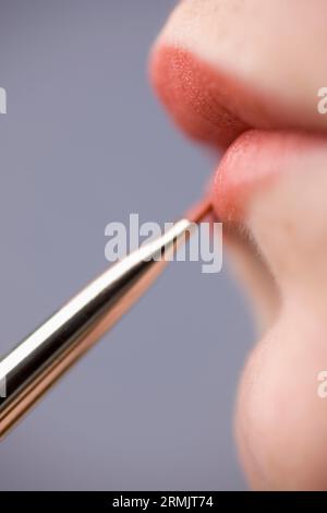 Nahaufnahme von junge Frau Lippen mit Lippenstift Pinsel Stockfoto