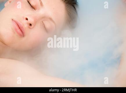 Nahaufnahme einer jungen schönen Frau mit geschlossenen Augen und Dampf Stockfoto