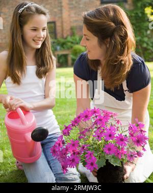 Mutter und Tochter im Garten Pflanzen Pflege und lächelnd kniend Stockfoto