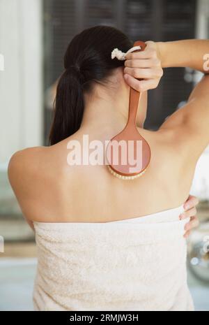 Rückseite der jungen Frau eingewickelt in Handtuch Peeling mit Pinsel Stockfoto
