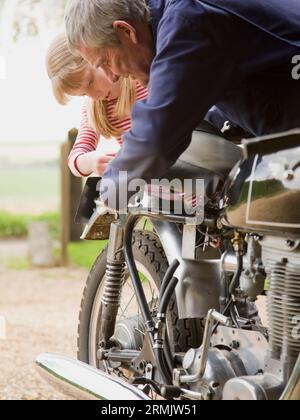 Junges Mädchen hilft Großvater Motorrad zu reparieren Stockfoto